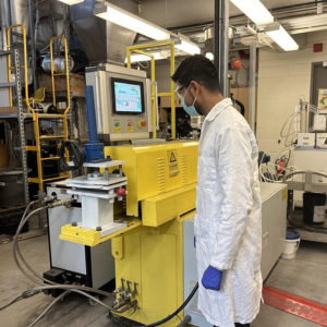 Man standing in a lab coat in front of equipment